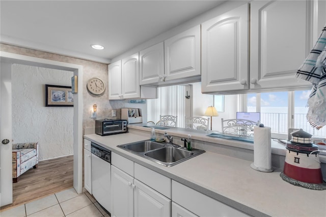 kitchen with light tile patterned floors, white dishwasher, sink, and white cabinets