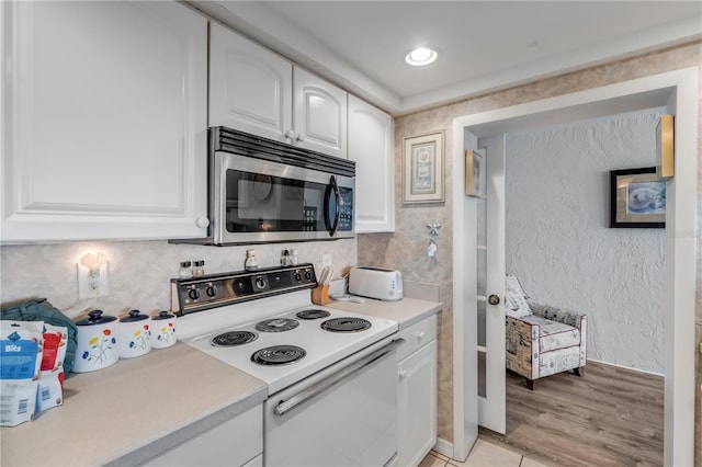 kitchen featuring tasteful backsplash, white cabinetry, light hardwood / wood-style floors, and electric stove