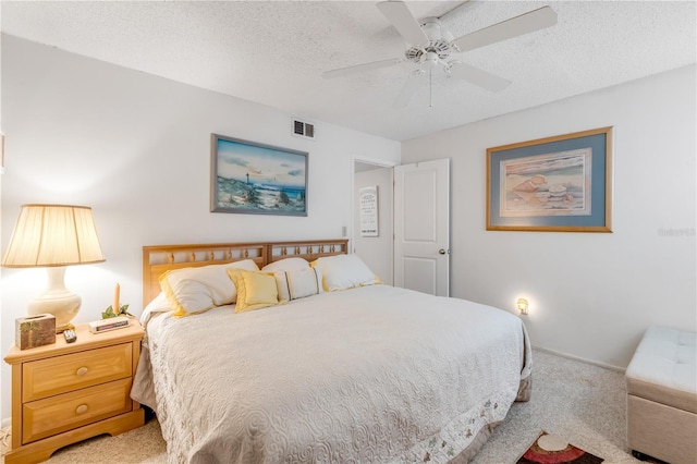 carpeted bedroom featuring ceiling fan and a textured ceiling