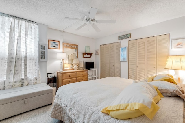 bedroom featuring ceiling fan, two closets, and a textured ceiling