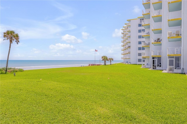 view of property's community featuring a view of the beach, a yard, and a water view