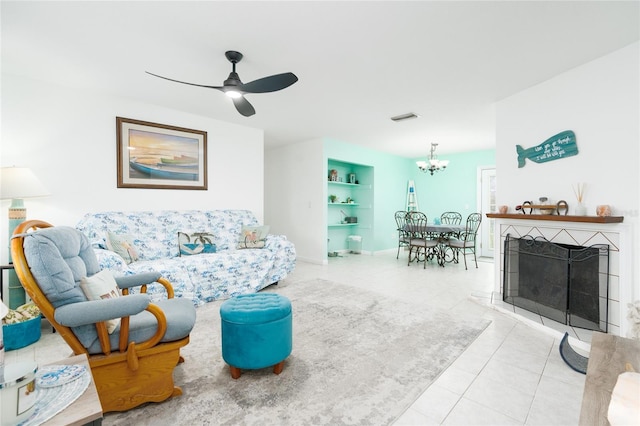 living room with light tile patterned floors, ceiling fan with notable chandelier, and built in features