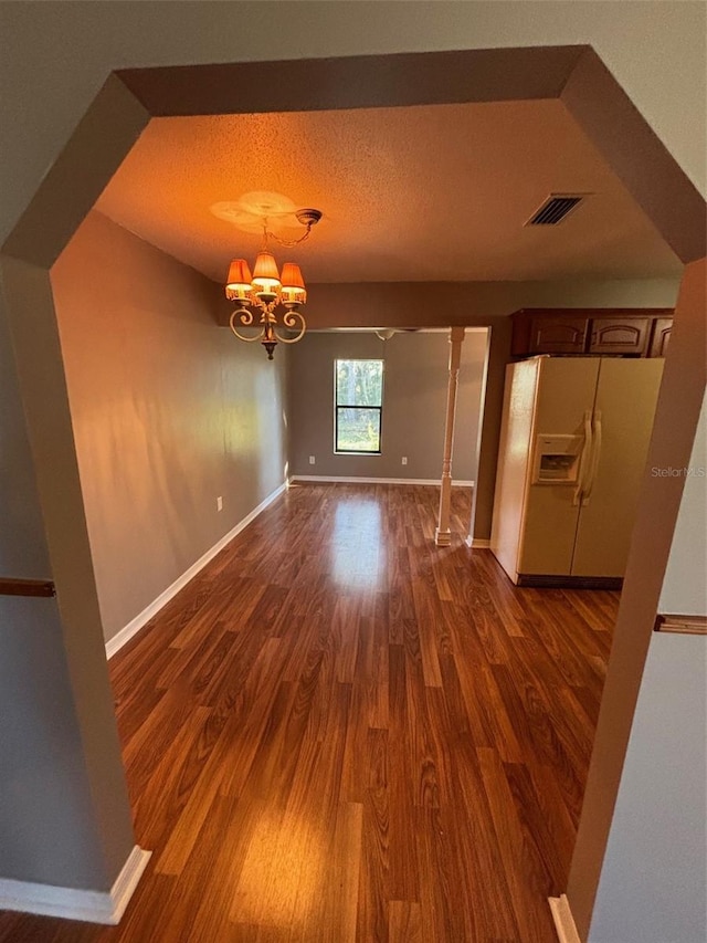 unfurnished dining area featuring an inviting chandelier and dark hardwood / wood-style flooring