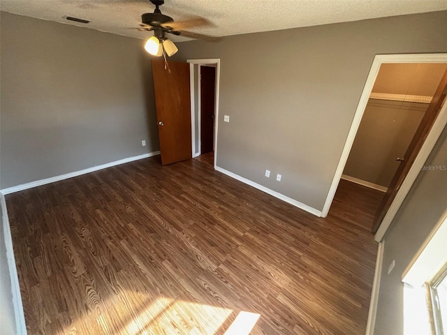 unfurnished bedroom featuring a walk in closet, dark hardwood / wood-style floors, a closet, and a textured ceiling