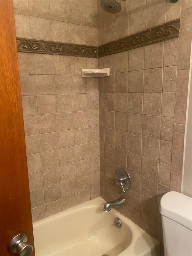 bathroom with toilet and tiled shower / bath combo