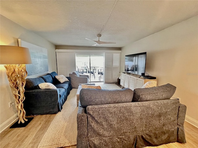 living room with ceiling fan, light hardwood / wood-style floors, and a textured ceiling