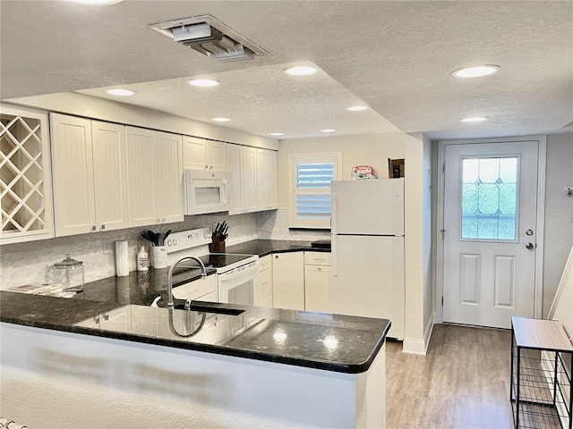 kitchen with white appliances, kitchen peninsula, and white cabinets