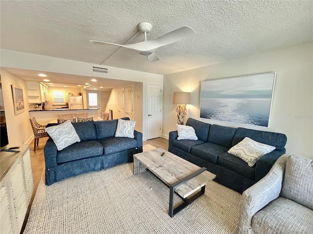 living room featuring a textured ceiling and ceiling fan