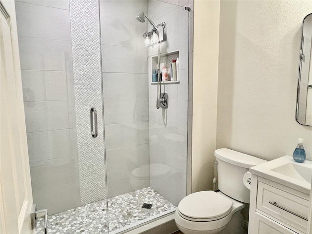 bathroom with an enclosed shower, vanity, and toilet