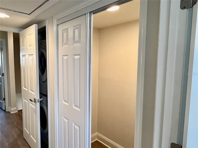 corridor with dark wood-type flooring and stacked washer / drying machine