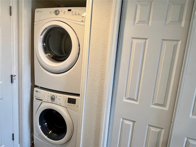 clothes washing area with stacked washing maching and dryer