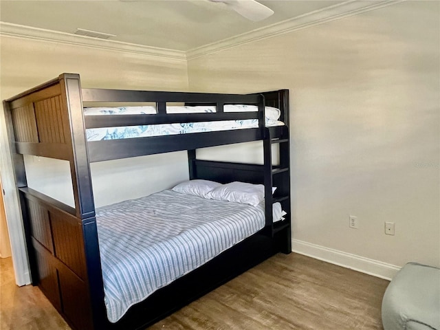 bedroom featuring ceiling fan, ornamental molding, and wood-type flooring