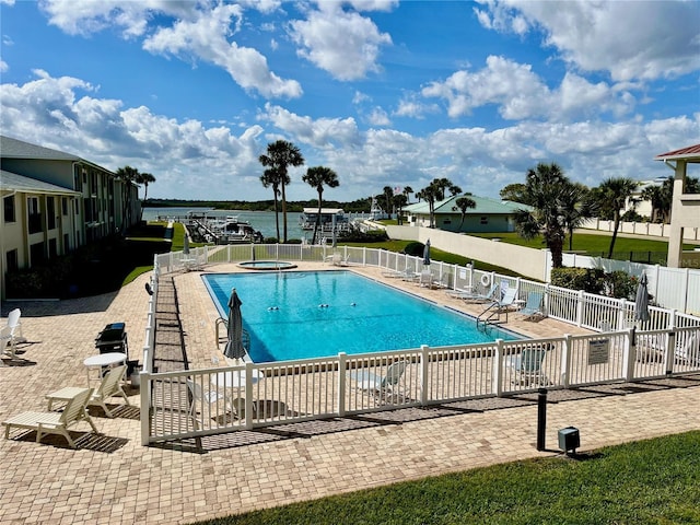 view of swimming pool featuring a patio area, a community hot tub, and a water view