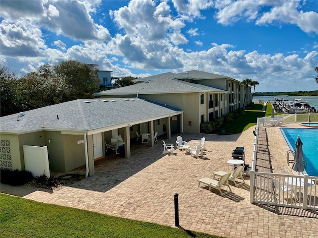 rear view of house featuring a fenced in pool, a water view, and a patio area