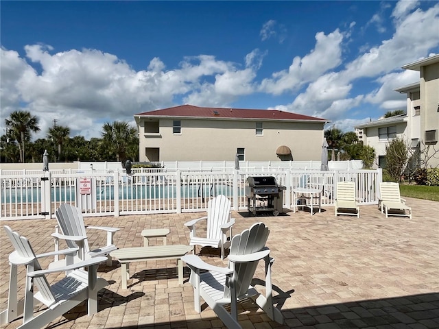 view of patio with a community pool, a grill, and a water view