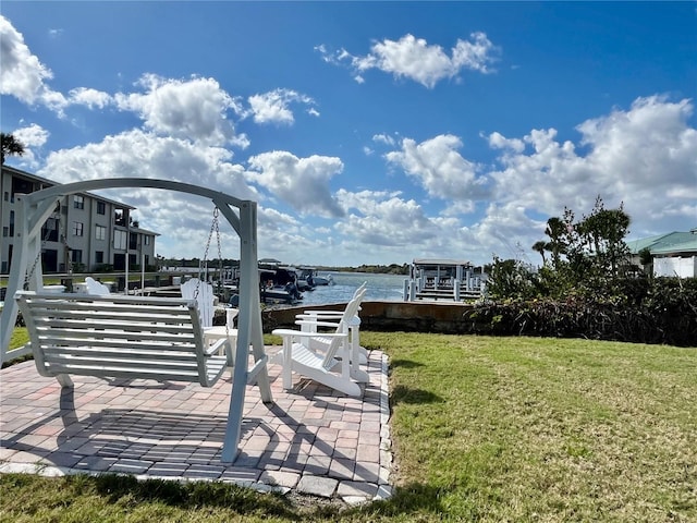 dock area with a patio, a water view, and a yard