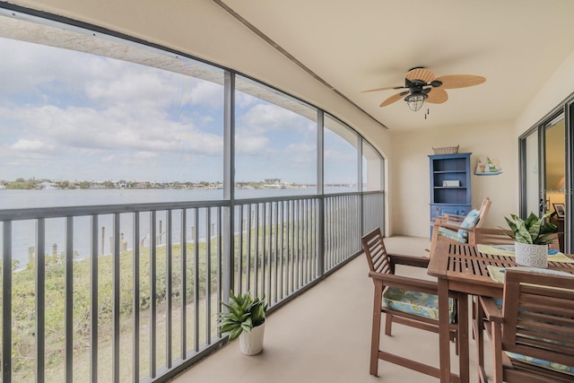 sunroom with a water view and ceiling fan