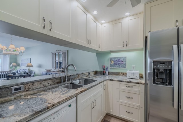 kitchen featuring light stone counters, sink, stainless steel fridge with ice dispenser, and white cabinets