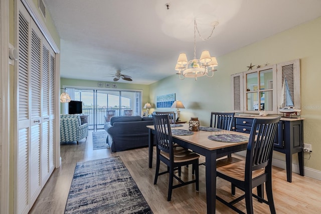 dining room with ceiling fan with notable chandelier and light hardwood / wood-style floors