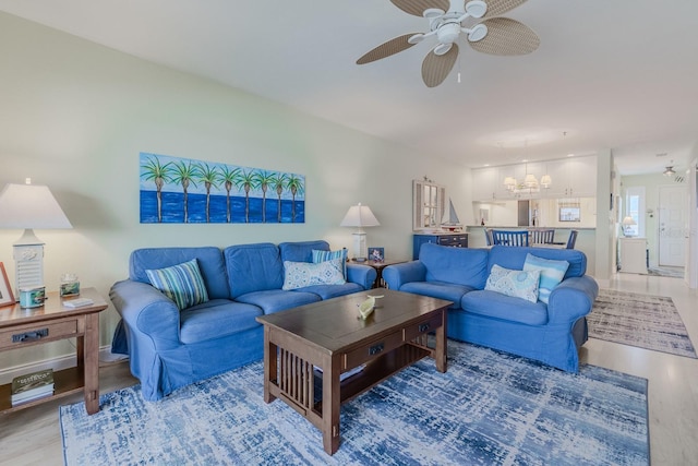 living room featuring ceiling fan with notable chandelier and light hardwood / wood-style flooring