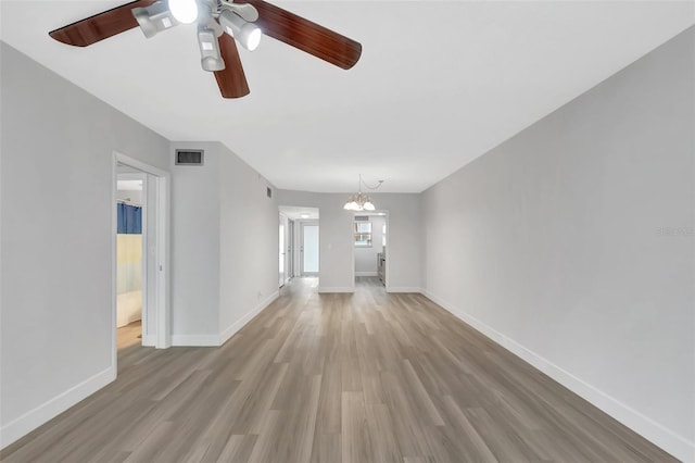 unfurnished living room featuring ceiling fan with notable chandelier and light hardwood / wood-style floors