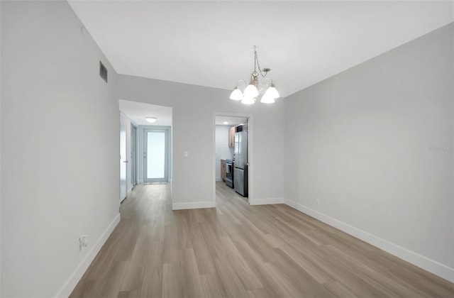 unfurnished dining area featuring a notable chandelier and light hardwood / wood-style flooring