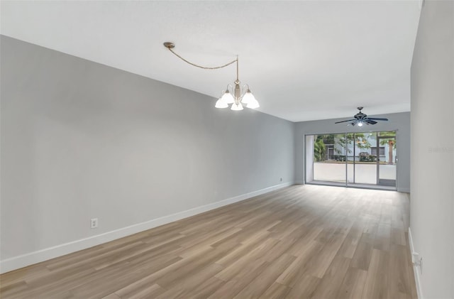 empty room featuring ceiling fan with notable chandelier and light hardwood / wood-style flooring