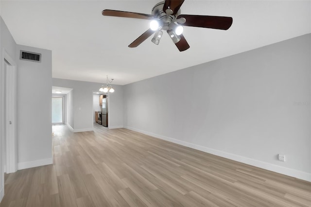 unfurnished living room with ceiling fan with notable chandelier and light wood-type flooring