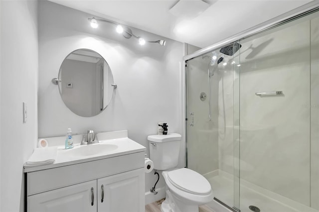 bathroom featuring vanity, a shower with door, and toilet