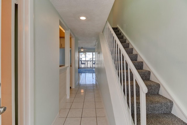 staircase featuring tile patterned floors and a textured ceiling