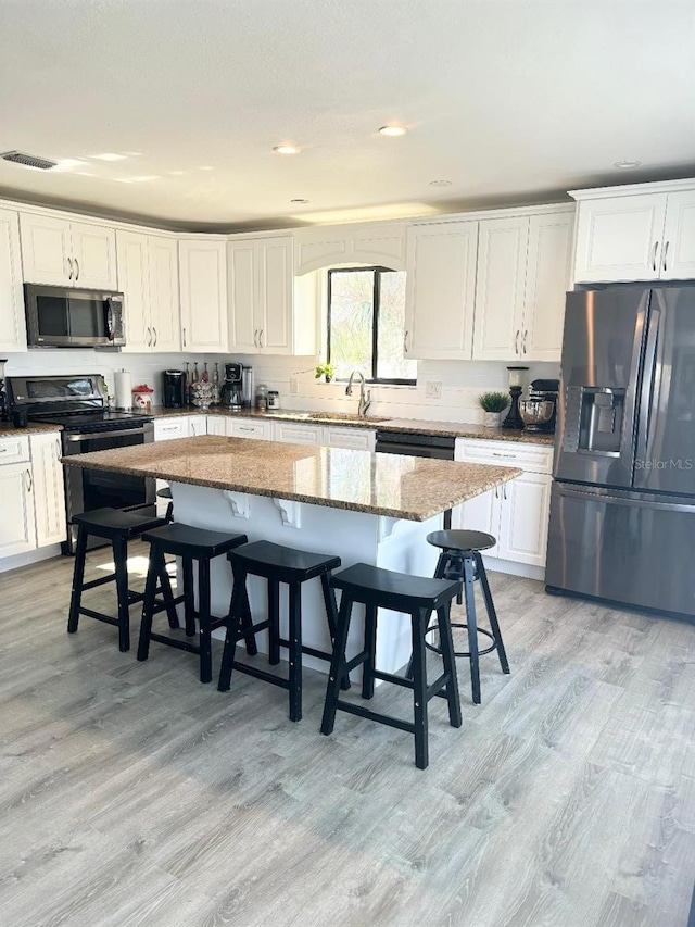 kitchen with a kitchen island, light stone countertops, a breakfast bar area, and appliances with stainless steel finishes