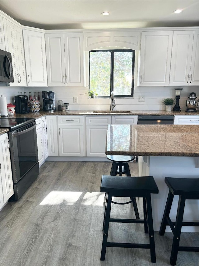 kitchen featuring white cabinetry, sink, black appliances, and light wood-type flooring