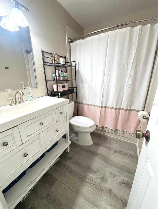 full bathroom with hardwood / wood-style flooring, shower / tub combo with curtain, vanity, and toilet