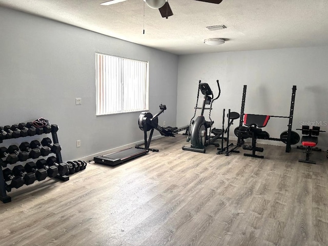 workout area featuring hardwood / wood-style flooring, ceiling fan, and a textured ceiling