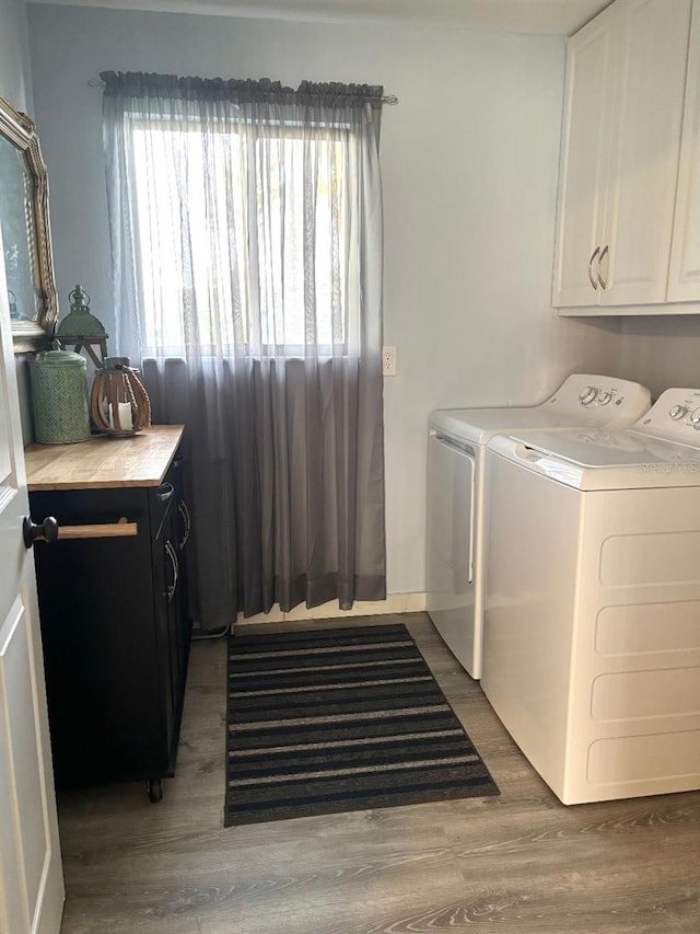 laundry area with cabinets, washing machine and clothes dryer, and hardwood / wood-style flooring