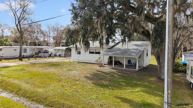 back of property featuring a lawn and a carport