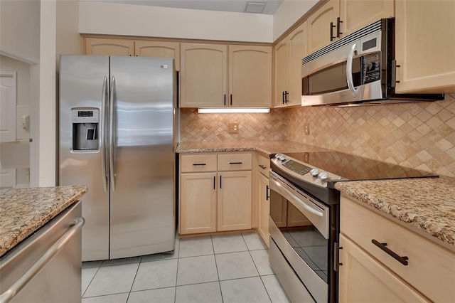 kitchen with light tile patterned flooring, light brown cabinetry, stainless steel appliances, light stone countertops, and backsplash