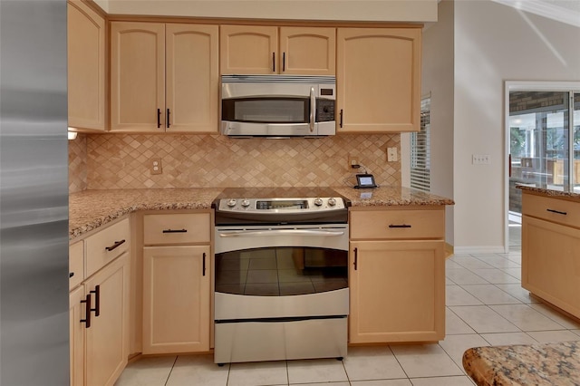 kitchen with light stone counters, stainless steel appliances, decorative backsplash, and light tile patterned floors