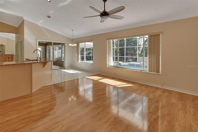 interior space featuring crown molding, vaulted ceiling, a textured ceiling, light hardwood / wood-style floors, and ceiling fan with notable chandelier