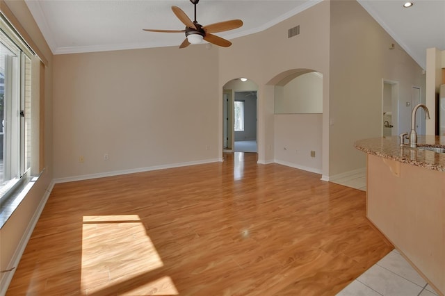 unfurnished living room featuring ceiling fan, ornamental molding, sink, and light tile patterned floors