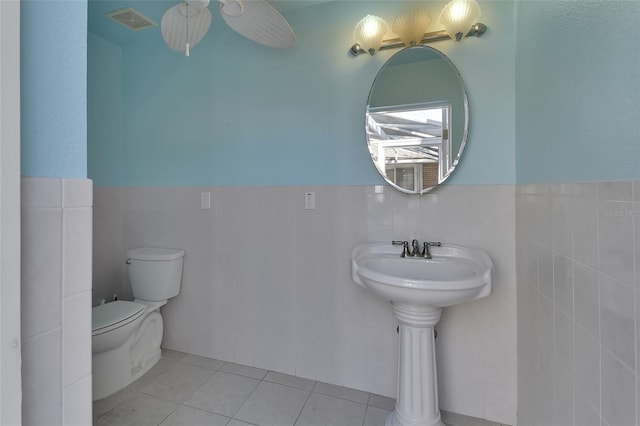 bathroom featuring tile walls, tile patterned floors, and toilet