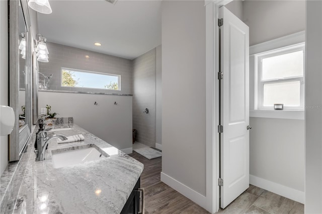 bathroom with tiled shower, vanity, and wood-type flooring