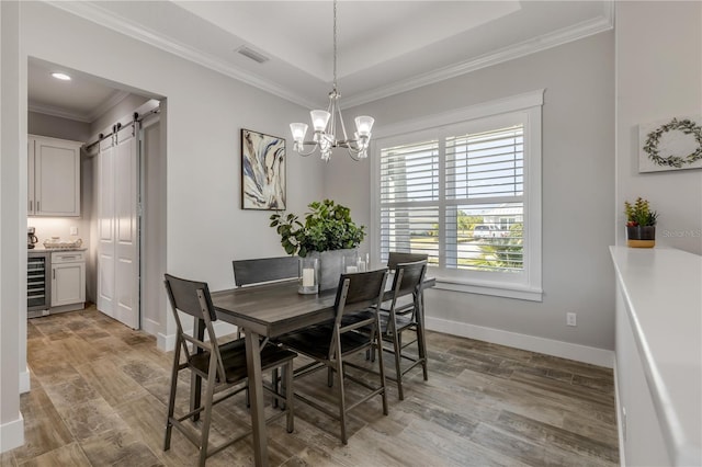 dining area with beverage cooler, a chandelier, a raised ceiling, crown molding, and a barn door