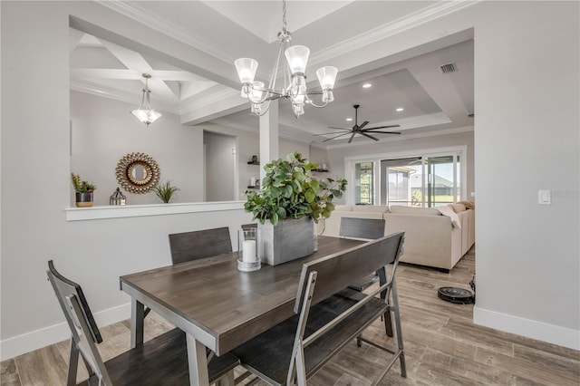 dining space featuring crown molding, hardwood / wood-style flooring, ceiling fan with notable chandelier, and a raised ceiling