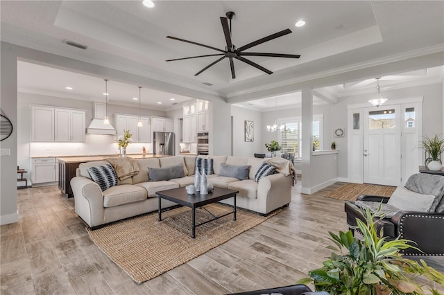 living room featuring crown molding, a tray ceiling, and light hardwood / wood-style flooring