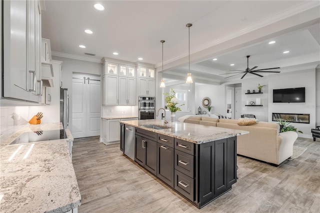 kitchen with sink, white cabinetry, hanging light fixtures, an island with sink, and stainless steel appliances