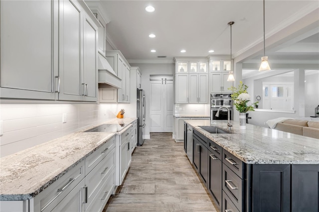 kitchen featuring tasteful backsplash, appliances with stainless steel finishes, a kitchen island with sink, and decorative light fixtures