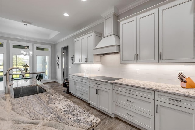 kitchen with black electric cooktop, sink, white cabinetry, and custom range hood