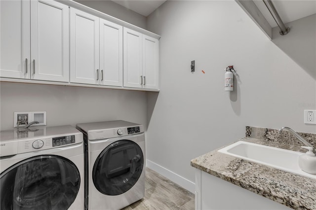 washroom with independent washer and dryer, cabinets, light hardwood / wood-style floors, and sink