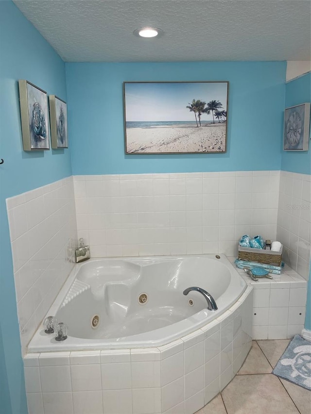 bathroom with tile patterned flooring, a relaxing tiled tub, and a textured ceiling